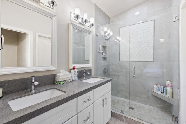 full bath with a sink, a stall shower, and double vanity