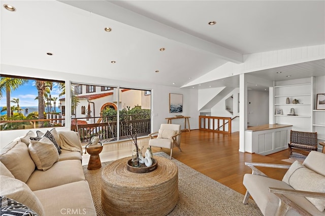 living area with a wealth of natural light, stairs, lofted ceiling with beams, and wood finished floors