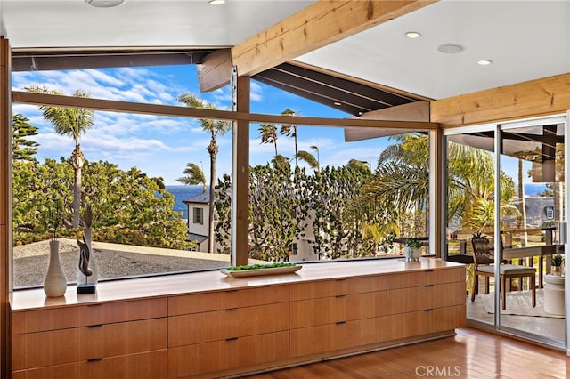 unfurnished sunroom featuring vaulted ceiling with beams