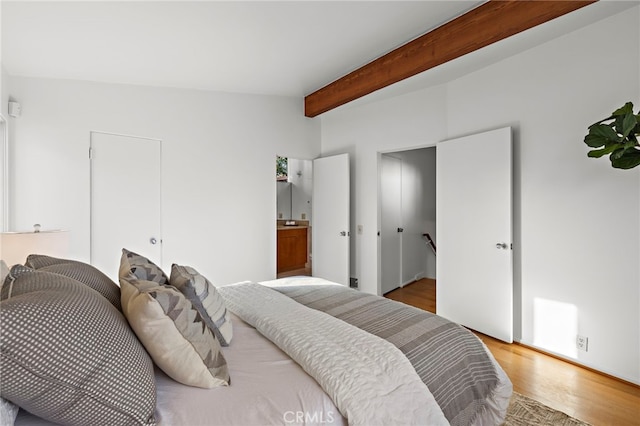 bedroom featuring lofted ceiling with beams and wood finished floors