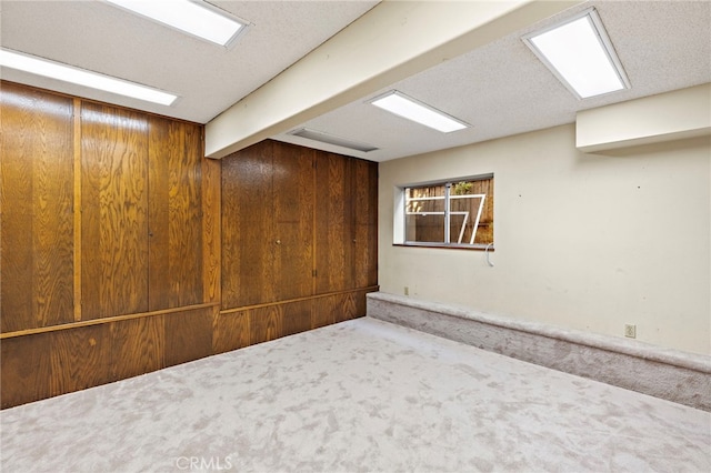 basement with carpet, wood walls, and a textured ceiling