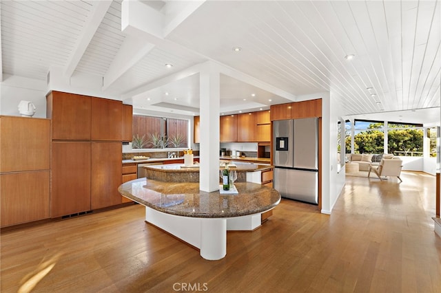 kitchen featuring dark stone counters, light wood-type flooring, appliances with stainless steel finishes, brown cabinetry, and modern cabinets