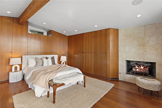 bedroom featuring recessed lighting, dark wood-style flooring, vaulted ceiling with beams, and a tile fireplace