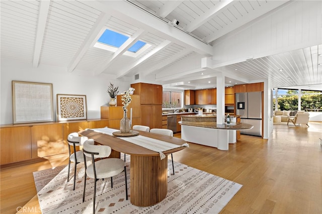 dining area featuring lofted ceiling with skylight, light wood-style floors, a wainscoted wall, and wooden ceiling