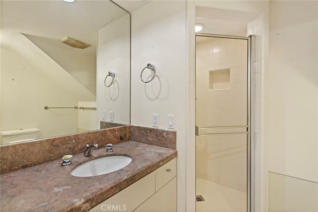 bathroom featuring vanity, a shower stall, toilet, and visible vents