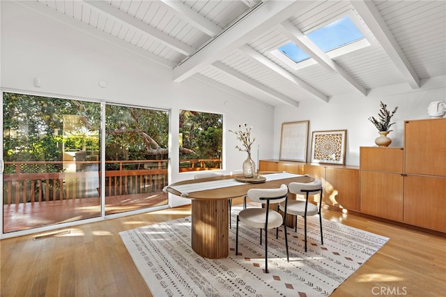 dining space with visible vents, vaulted ceiling with skylight, and light wood-style floors