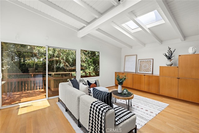 living area featuring vaulted ceiling with skylight, light wood-style floors, and visible vents