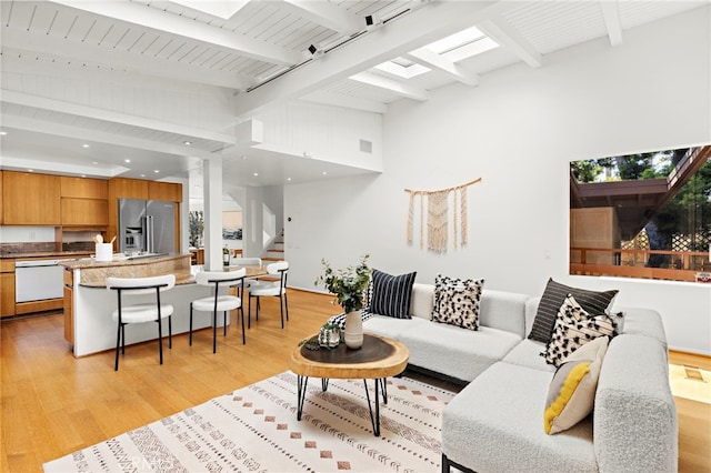 living area featuring visible vents, beamed ceiling, stairs, light wood-style floors, and high vaulted ceiling