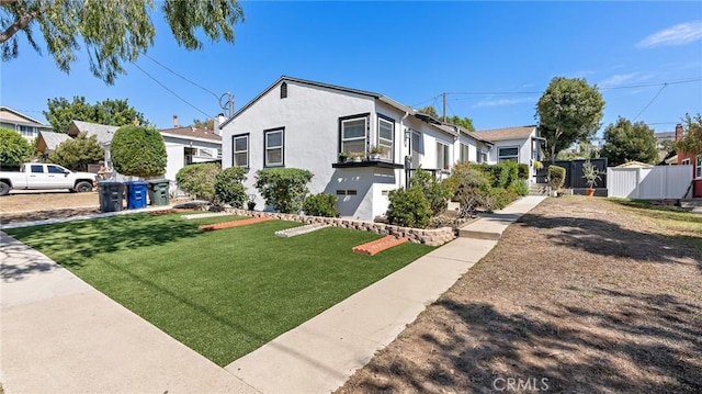 bungalow with stucco siding, a front yard, and fence