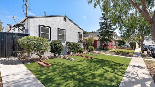 exterior space featuring a front yard, a gate, fence, and stucco siding