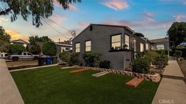 property exterior at dusk with a yard and stucco siding