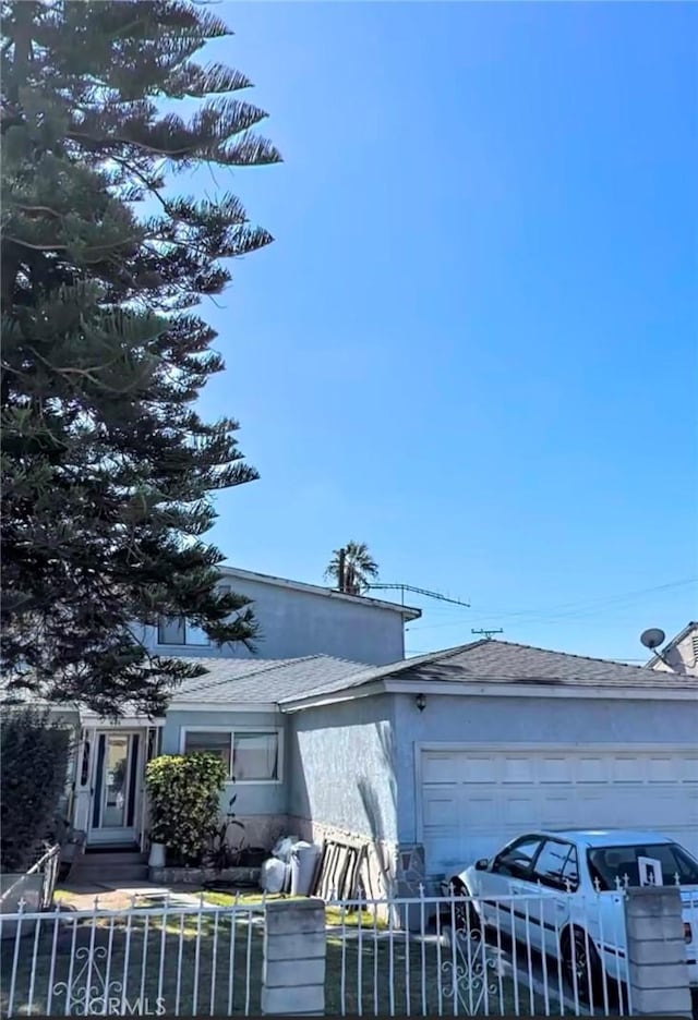 view of front of home featuring a fenced front yard, concrete driveway, an attached garage, and stucco siding