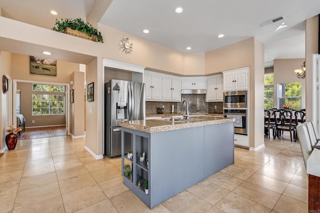 kitchen with light stone countertops, visible vents, white cabinets, appliances with stainless steel finishes, and tasteful backsplash