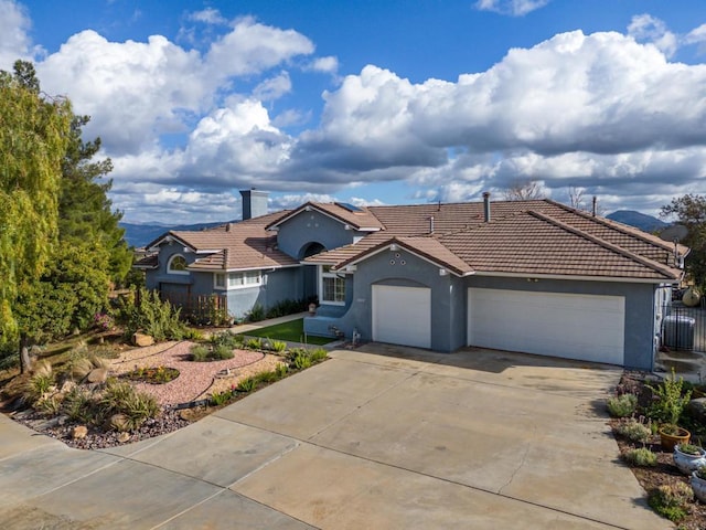 view of front of property featuring fence, an attached garage, stucco siding, concrete driveway, and a tiled roof