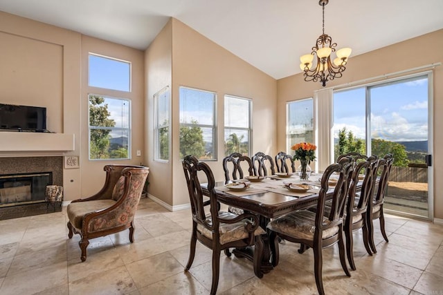 dining area with baseboards, plenty of natural light, an inviting chandelier, and a fireplace