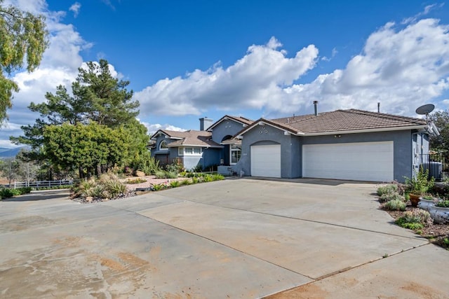 ranch-style home with fence, stucco siding, concrete driveway, a garage, and a tile roof