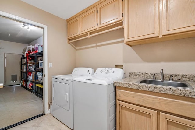 washroom featuring washing machine and clothes dryer, cabinet space, light tile patterned flooring, and a sink