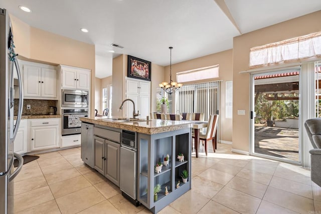 kitchen with a sink, an inviting chandelier, white cabinets, and stainless steel appliances