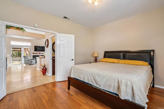 bedroom with wood finished floors, visible vents, and baseboards