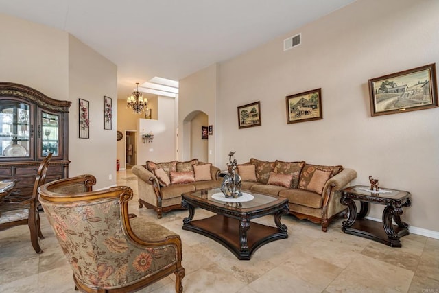 living area with baseboards, visible vents, arched walkways, and an inviting chandelier