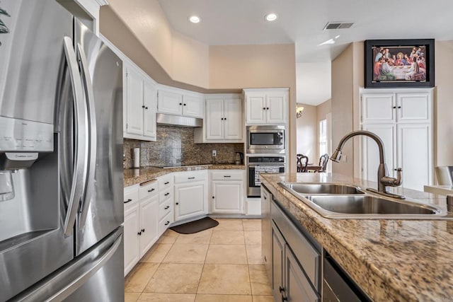 kitchen featuring visible vents, a sink, stainless steel appliances, under cabinet range hood, and tasteful backsplash