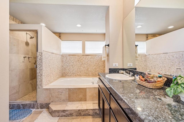 bathroom with vanity, a bath, tasteful backsplash, and a tile shower