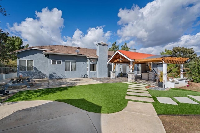 rear view of house featuring stucco siding, a lawn, a patio area, a chimney, and a tiled roof