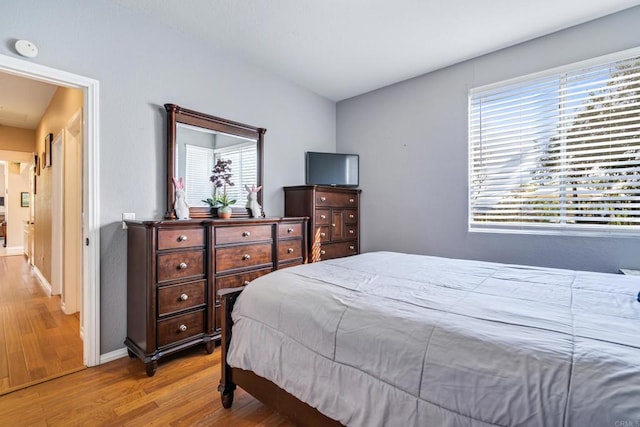 bedroom featuring baseboards, multiple windows, and wood finished floors