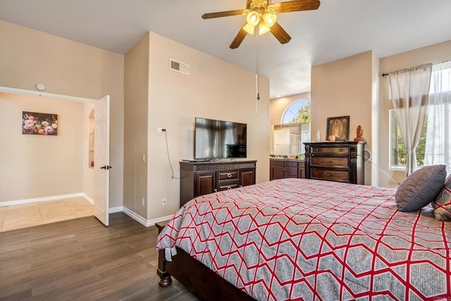 bedroom featuring ceiling fan, visible vents, baseboards, and wood finished floors