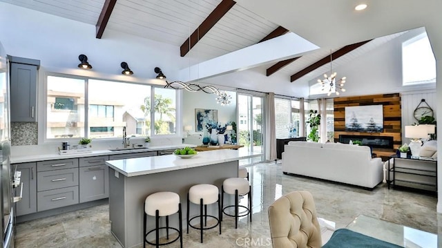 kitchen featuring a kitchen bar, gray cabinets, a sink, open floor plan, and light countertops