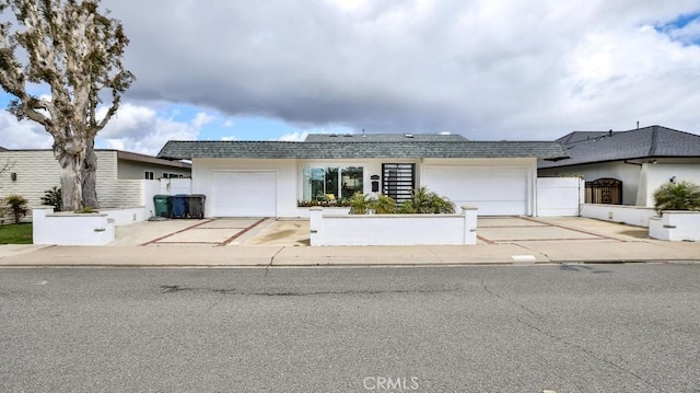 view of front of house with stucco siding, concrete driveway, an attached garage, and fence