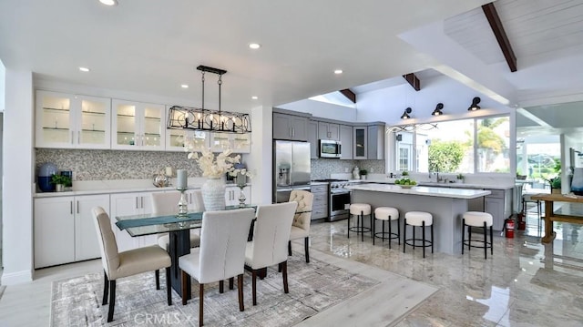 dining area with an inviting chandelier, lofted ceiling with beams, recessed lighting, and marble finish floor