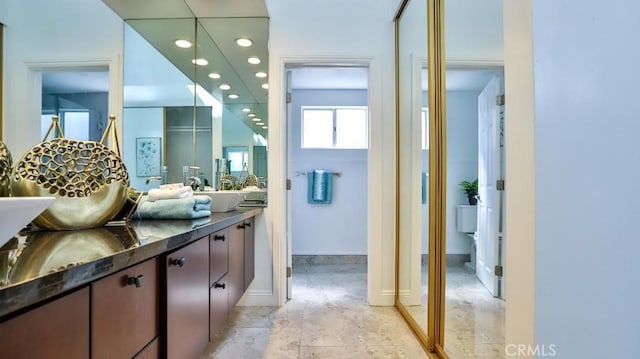 bathroom with double vanity, recessed lighting, baseboards, and a sink