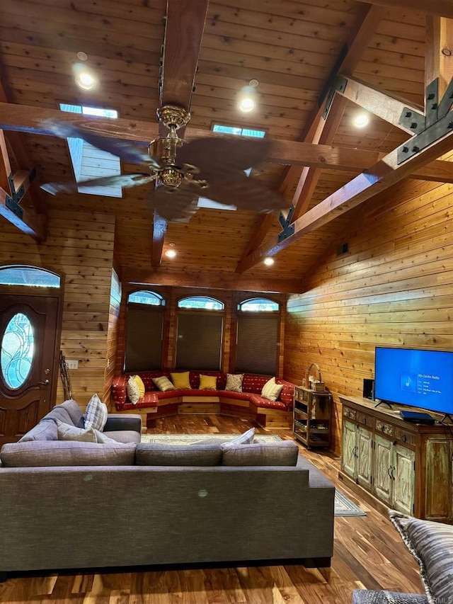 living room featuring wooden walls, ceiling fan, beamed ceiling, wood ceiling, and wood finished floors