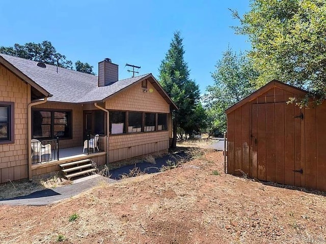 view of home's exterior with roof with shingles and a chimney