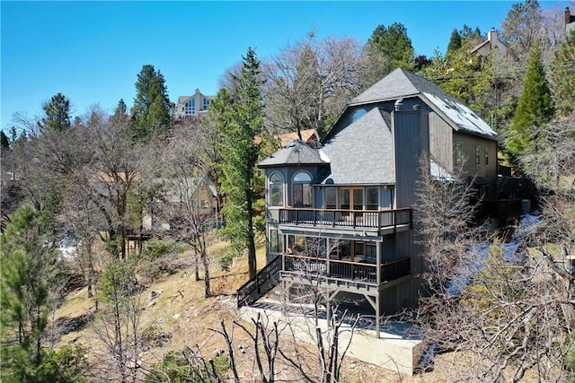 rear view of house featuring a deck and roof with shingles