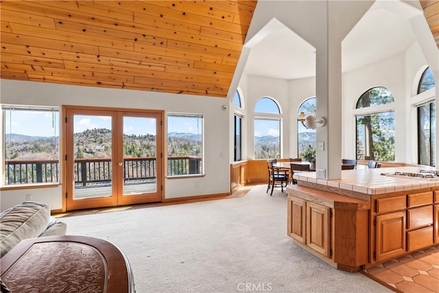 interior space with wooden ceiling, light colored carpet, baseboards, and high vaulted ceiling