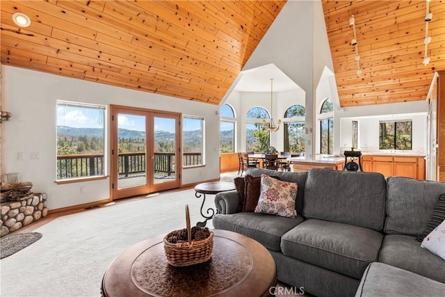 living area featuring high vaulted ceiling, a mountain view, baseboards, light colored carpet, and wood ceiling