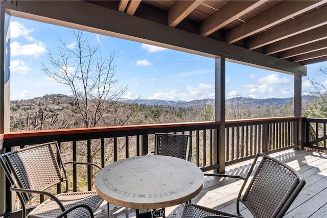 deck with a mountain view and outdoor dining area