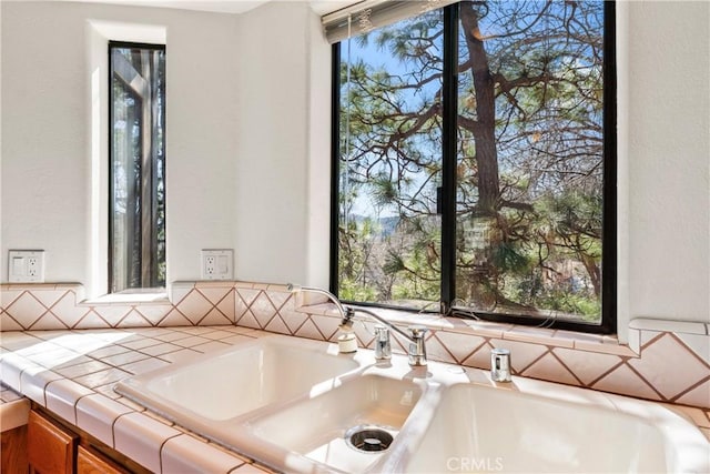 interior space with brown cabinetry, a sink, and tile counters