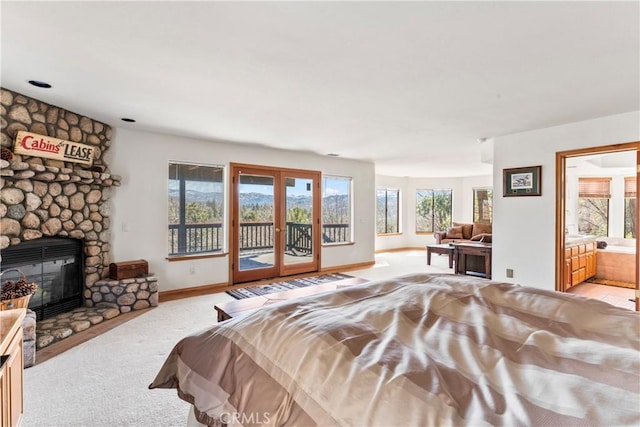 bedroom featuring baseboards, a stone fireplace, access to exterior, french doors, and light colored carpet