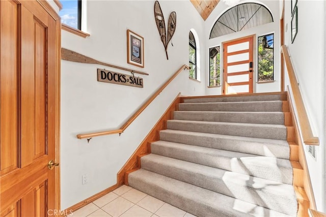 staircase featuring tile patterned flooring, lofted ceiling, and baseboards