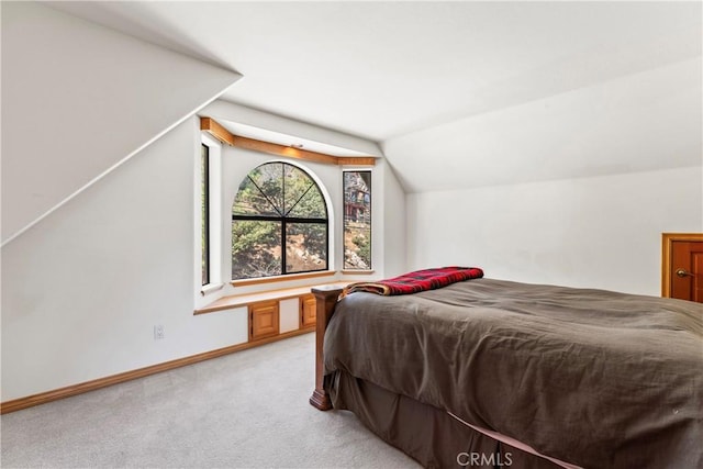 bedroom with vaulted ceiling, light colored carpet, and baseboards