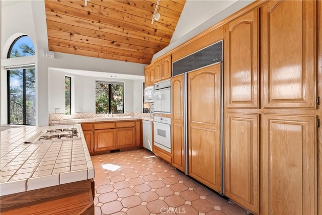 kitchen featuring visible vents, tile countertops, vaulted ceiling, wooden ceiling, and white appliances