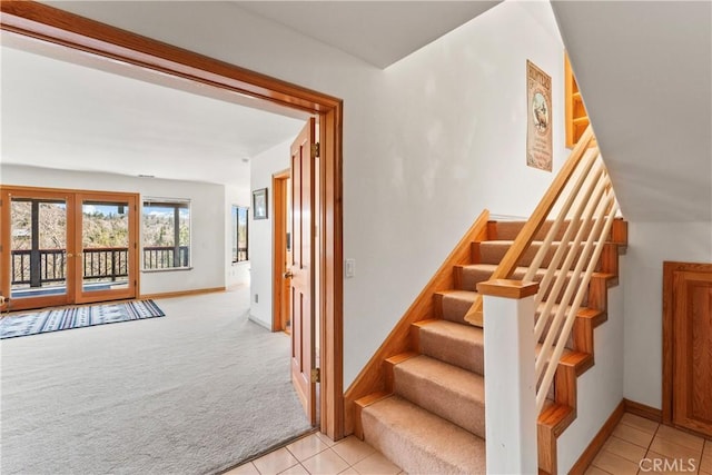 staircase with tile patterned floors, french doors, baseboards, and carpet flooring