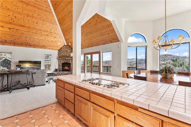 kitchen with tile counters, white cooktop, light colored carpet, open floor plan, and a chandelier