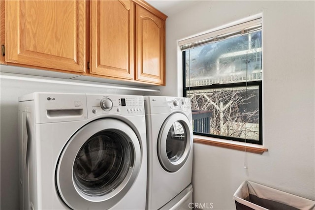 clothes washing area with washer and dryer and cabinet space