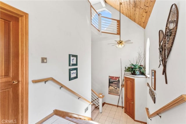 stairs featuring tile patterned floors, visible vents, a ceiling fan, baseboards, and lofted ceiling