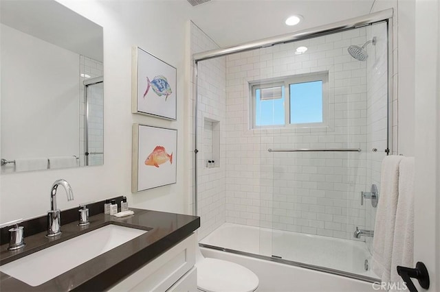 full bathroom featuring vanity, toilet, and shower / bath combination with glass door