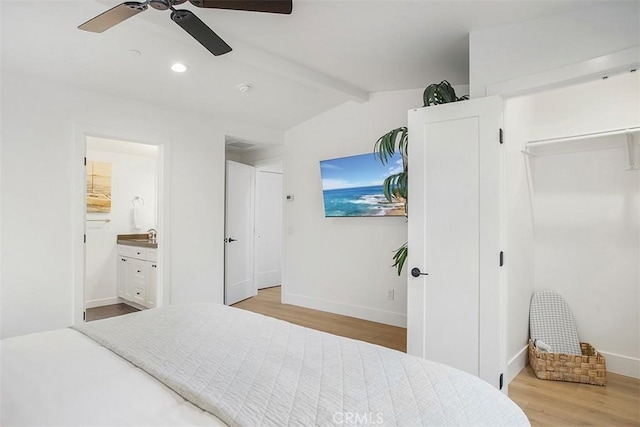 bedroom featuring a ceiling fan, wood finished floors, baseboards, lofted ceiling with beams, and connected bathroom